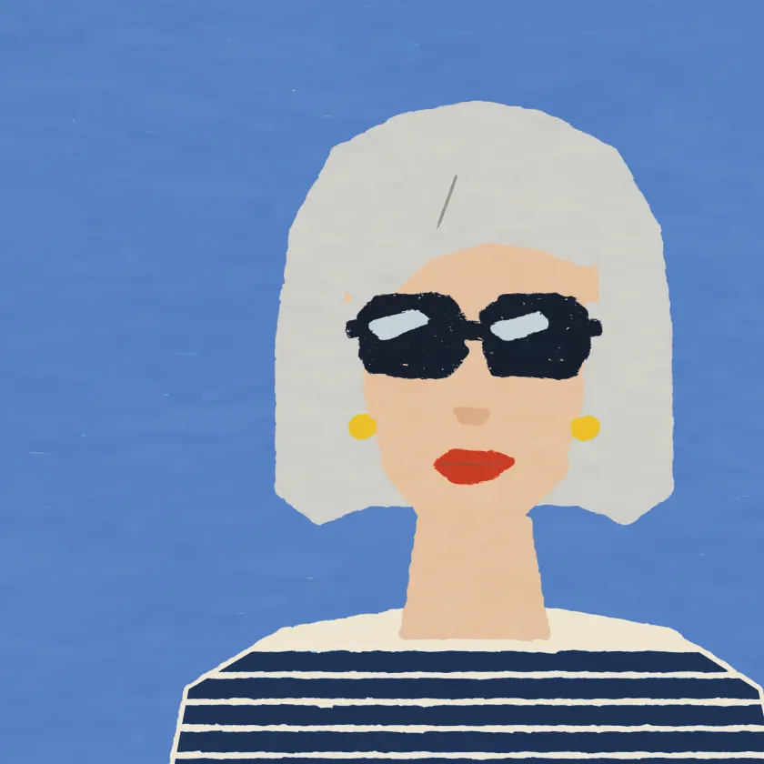 A woman with a silver bob, dark sunglasses, red lipstick and a striped top.